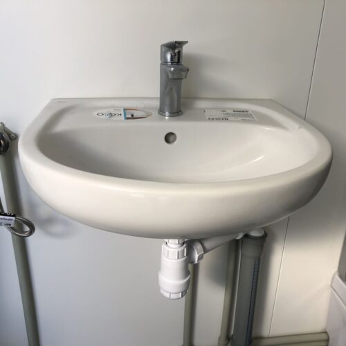 js8 Contentor sanitário com chuveiro, lavatório e sanita.