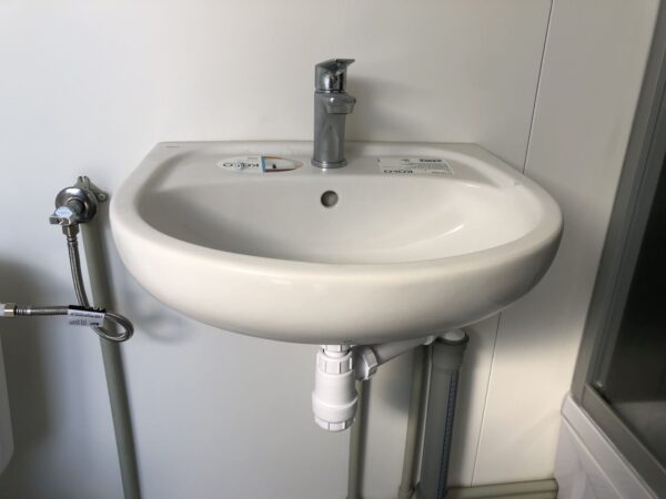 js8 Contentor sanitário com chuveiro, lavatório e sanita.